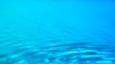 Su ve ışık yaratıcı reklam konsepti. Su yüzeyinin yakın çekim stüdyosu. Güzel, sakin, berrak, mavi bir su yüzeyi. Işık kıvılcımları hareket ederek daireler ve dalgalar oluşturuyor. Yavaş çekim.