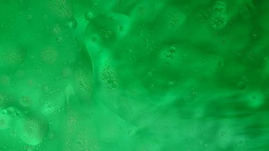 Su ve sıvılar soyut reklam konsepti. Yüzey dokusunun yakın çekim görüntüsü. Sıvı parlak yağ güzel yeşil renkli su yüzeyinde akar, soyut arka plan, duvar kağıdı şablonu.