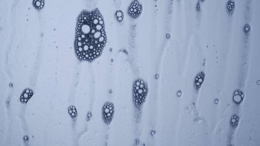 Su ve karışık malzemeler yaratıcı ve soyut bir kavram. Aqua 'nın yakın çekim stüdyosu. Beyaz köpük kabarcıkları yüzeyden akarak yağmurlu bir etki yaratıyor, güzel soyut bir arka plan..