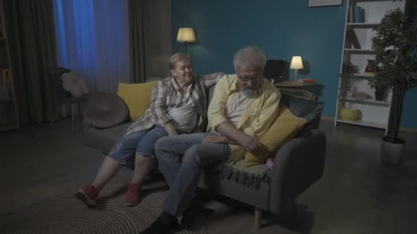 Imagen Pareja Ancianos Sientan Sofá Apartamento Contra Pared Azul Hombre — Vídeo de stock