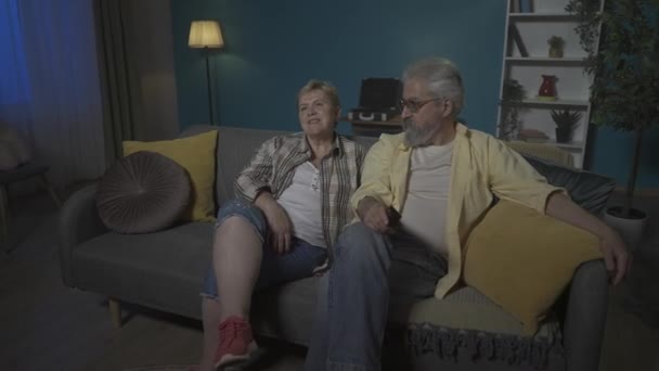 Elderly Couple Sitting Sofa Apartment Look Away Watch Movie Transmission — Stock Video