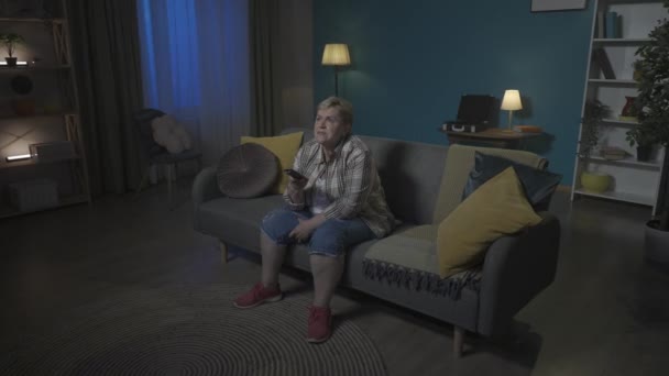 소파에 앉아있는 여성의 사진에서 그녀는 Tv에 채널을 전환하고 그녀가 선택합니다 — 비디오