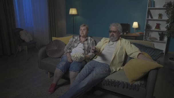 Elderly Couple Sitting Eating Popcorn Watching Movie Program Woman Bored — Stock Video