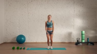 Evde kişisel spor eğitimleri. Spor giyimli bir kadın spor yapıyor. Sağlık ve sağlık reklamları konsepti. Atletik kadın fitness koçu çevrimiçi dersler için atlama yapıyor..