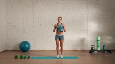 Evde kişisel spor eğitimleri. Spor giyimli bir kadın spor yapıyor. Sağlık ve sağlık reklamları konsepti. Atletik kadın fitness koçu çevrimiçi dersler için yüksek diz atlamaları yapıyor..