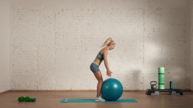 Evde kişisel spor eğitimleri. Spor giyimli bir kadın spor yapıyor. Sağlık ve sağlık reklamları konsepti. Atletik kadın fitness koçu çevrimiçi dersler için topla dönüşler yapıyor..