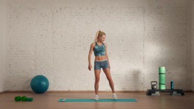 Evde kişisel spor eğitimleri. Spor giyimli bir kadın spor yapıyor. Sağlık ve sağlık reklamları konsepti. Atletik kadın fitness koçu çevrimiçi dersler için bacak bacak kaldırma hareketi yapıyor..