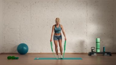 Evde kişisel spor eğitimleri. Spor giyimli bir kadın spor yapıyor. Sağlık ve sağlık reklamları konsepti. Atletik kadın fitness koçu çevrimiçi dersler için lastik bant kolu kaldırıyor..
