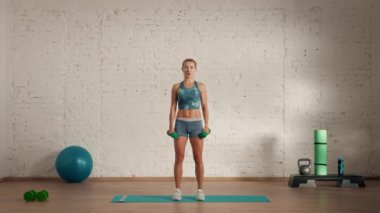 Evde kişisel spor eğitimleri. Spor giyimli bir kadın spor yapıyor. Sağlık ve sağlık reklamları konsepti. Atletik kadın spor koçu dambıllarla düz kollar kaldırıyor..