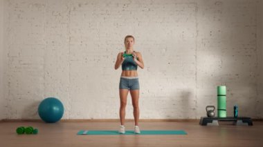 Evde kişisel spor eğitimleri. Spor giyimli bir kadın spor yapıyor. Sağlık ve sağlık reklamları konsepti. Atletik kadın fitness koçu başındaki trisepsleri kaldırıyor..