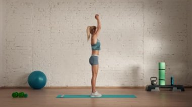 Evde kişisel spor eğitimleri. Spor giyimli bir kadın spor yapıyor. Sağlık ve sağlık reklamları konsepti. Atletik kadın fitness koçu halterlerle trisepsi kaldırıyor..
