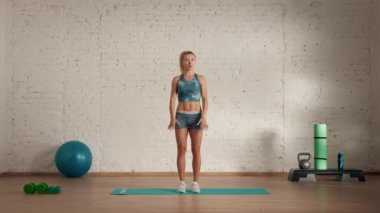 Evde kişisel spor eğitimleri. Spor giyimli bir kadın spor yapıyor. Sağlık ve sağlık reklamları konsepti. Atletik kadın fitness koçu çevrimiçi dersler için atlama hareketleri yapıyor..