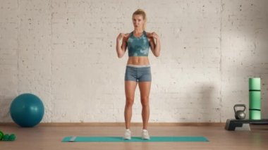 Evde kişisel spor eğitimleri. Spor giyimli bir kadın spor yapıyor. Sağlık ve sağlık reklamları konsepti. Atletik kadın fitness koçu online dersler için diz kaldırma egzersizi yapıyor..