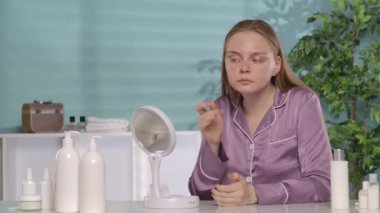 Genç bir kadın aynada yüzüne bakar ve sonuçtan memnun bir şekilde gülümser. Bir kadın bir kavanoz krema gösteriyor, tavsiye ediyor. Makyajsız ve ipek pijamalı bir kadın tuvalet masasında oturuyor.