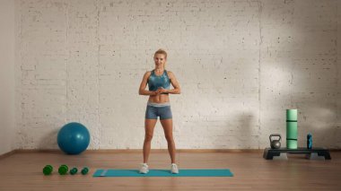 Evde online olarak kişisel spor dersleri. Spor giyim bölümünde egzersiz yapan sarışın bir kadın. Sağlık hizmetleri yaratıcı reklam konsepti. Kadın fitness koçu odada kameraya bakıyor..