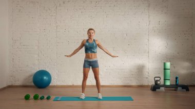 Evde online olarak kişisel spor dersleri. Spor giyim bölümünde egzersiz yapan sarışın bir kadın. Sağlık hizmetleri yaratıcı reklam konsepti. Kadın jimnastik hocası elleri açık odada duruyor..