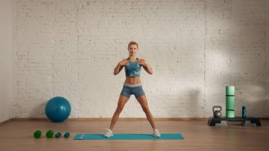 Evde online olarak kişisel spor dersleri. Spor giyim bölümünde egzersiz yapan sarışın bir kadın. Sağlık hizmetleri yaratıcı reklam konsepti. Kadın jimnastik koçu odada el ele tutuşup duruyor..
