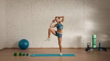 Evde online olarak kişisel spor dersleri. Spor giyim bölümünde egzersiz yapan sarışın bir kadın. Sağlık hizmetleri yaratıcı reklam konsepti. Kadın fitness koçu yan dizlerini kaldırıyor..