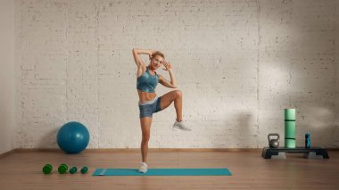 Evde online olarak kişisel spor dersleri. Spor giyim bölümünde egzersiz yapan sarışın bir kadın. Sağlık hizmetleri yaratıcı reklam konsepti. Kadın fitness koçu odada yan dizlerini kaldırıyor..