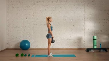Evde online olarak kişisel spor dersleri. Spor giyim bölümünde egzersiz yapan sarışın bir kadın. Sağlık hizmetleri yaratıcı reklam konsepti. Kadın jimnastik koçu odada. Kettlebell 'le dikiliyor..