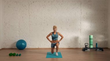 Evde online olarak kişisel spor dersleri. Spor giyim bölümünde egzersiz yapan sarışın bir kadın. Sağlık hizmetleri yaratıcı reklam konsepti. Kadın fitness koçu salonda bacak hareketlerini yapıyor..