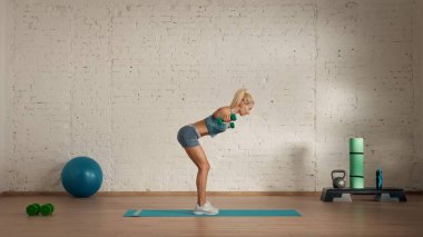 Evde online olarak kişisel spor dersleri. Spor giyim bölümünde egzersiz yapan sarışın bir kadın. Sağlık hizmetleri yaratıcı reklam konsepti. Kadın fitness koçu salonda halterleri yarım büküyor..