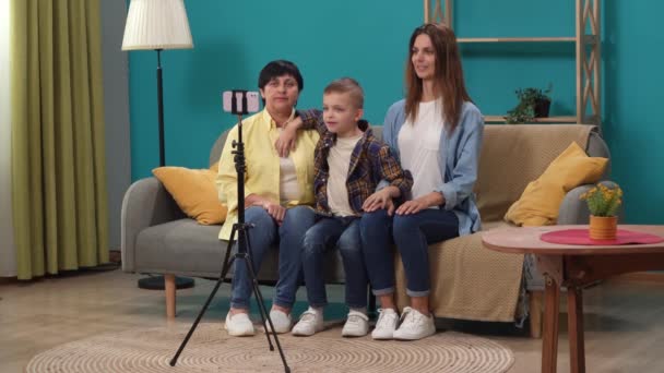 老年人家庭日常生活创意的概念 一家人的画像 女儿和孙子孙女坐在沙发上 拿着三脚架用智能手机自拍的特写镜头 — 图库视频影像