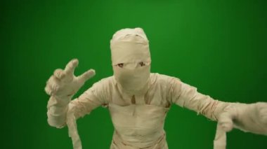 Yeşil ekran, kollarını açmış, birini yakalamaya çalışan bir mumyanın kameraya doğru koştuğunu gösteren krom anahtar videosunu izole etti. Terfi videon ya da reklamın için hazırlan. Orta boyut.