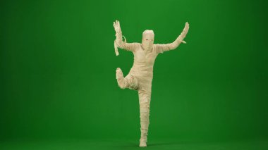 Sargı bezine sarılmış bir mumya, kolları ve bacağı havada poz verir. Yeşil ekran izole edilmiş kroma anahtarı. Model, çalışma alanı, reklam. Tam boy. Cadılar Bayramı.