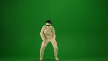 Bandajlara sarılı korkunç mumya siyah şapka ve güneş gözlüğü takıyor. Yeşil ekran, krom anahtar. Model yapın, tanıtım videonuz ya da reklamınız için çalışma alanı. Tam boy. Cadılar Bayramı.