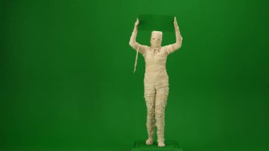 Yeşil ekran, yeşil ekran pankart taşıyan ürpertici bir mumyayı yakalayan krom anahtar fotoğrafı. Terfi videon ya da reklamın için hazırlan. Tam uzunluk.