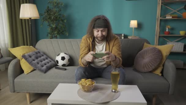 Marco Hombre Está Sentado Sofá Sostiene Teléfono Mira Mostrando Fútbol — Vídeo de stock