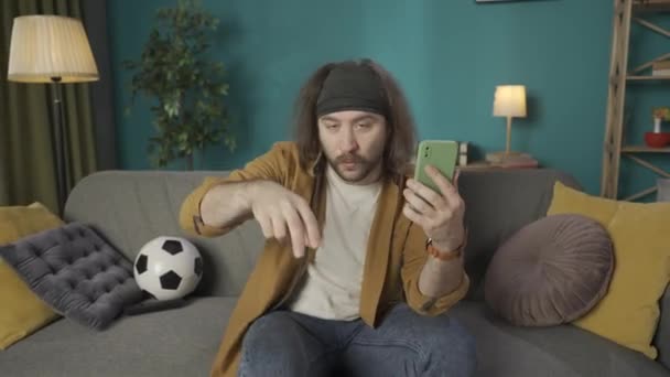Homem Meia Idade Está Sentado Sofá Segurando Telefone Conversando Com — Vídeo de Stock