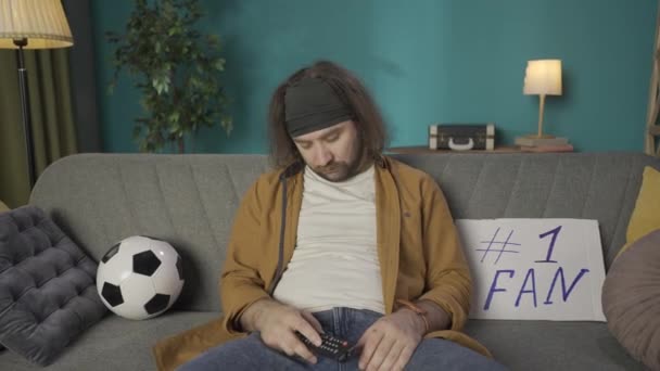 在镜头中 一个中年男人坐在沙发上打瞌睡 旁边躺着一个标志和一个球 他突然醒来 兴高采烈地喝啤酒 观看一场足球赛的示范 Hdr — 图库视频影像