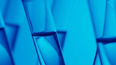 Laboratuvarda fuild ile doldurulmuş mavi ışık test tüplerini kapatın. Bilimsel deney, araştırma, çalışma. Laboratuvar cam takımının detaylı görüntüsü. Yaratıcı içerik veya tıbbi reklam.