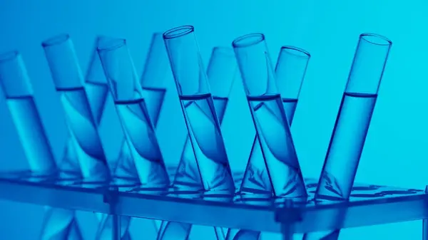 Close up video neon blue light test tubes filled with fuild in a laboratory. Scientific experiment, research, study. Detail shot of lab glassware. Creative content or medical advertisement.