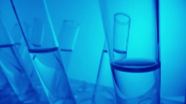 Laboratuvarda fuild ile doldurulmuş mavi ışık test tüplerini kapatın. Bilimsel deney, araştırma, çalışma. Laboratuvar cam takımının detaylı görüntüsü. Yaratıcı içerik veya tıbbi reklam.