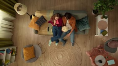 Genç bir çiftin kanepede oturup film izlemesi, TV 'de film çekmesi, aktif olarak tartışması ve patlamış mısır yemesi. Aile, eğlence, ev sineması, televizyon, komedi ve drama.