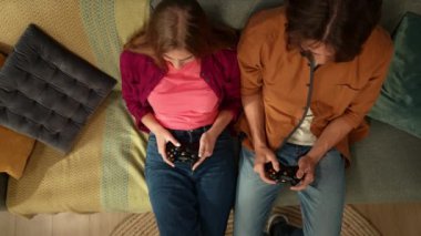 Kanepede oturan genç bir çiftin oyun kağıtlarını tutarken birlikte video oyunu oynuyorlarmış gibi görünmeleri. Adam oyunu kazanmış gibi görünüyor. Aile, eğlence ve hobiler, oyun..