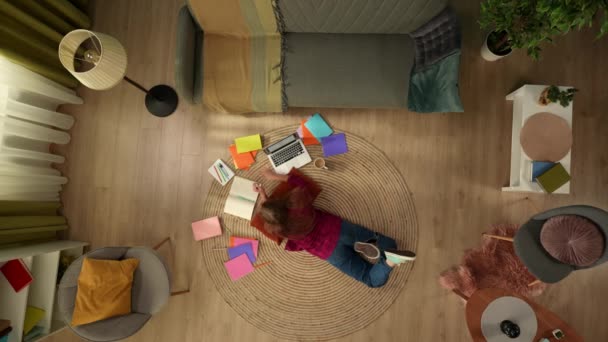 바닥에 공부하는 여자를 노트북에서 작업하고 메모를 다채로운 책으로 둘러싸여 Homeschooling — 비디오