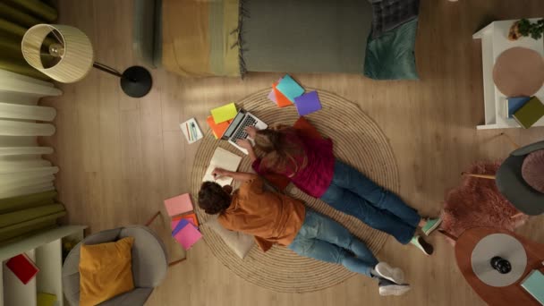 바닥에 공부하는 커플을 캡처하고 노트북에서 작업하고 메모를 다채로운 책으로 둘러싸여 — 비디오