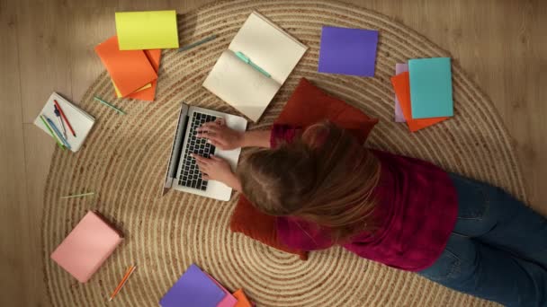 头像是一个年轻女子躺在地板上学习 在笔记本电脑上工作 做笔记 周围环绕着五彩斑斓的书籍 学院和大学 家庭教育 在线教育 — 图库视频影像