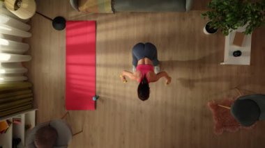 Üst manzara, sabah egzersizini yapan genç bir kadını pencerenin önünde dambıllarla yakalıyor. Ev, ev içi aktiviteler. Sağlıklı ve aktif yaşam tarzı, sabah rutini, hedeflere ulaşmak..