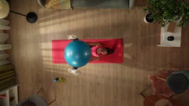 Genç bir kadının mavi bir egzersiz topuyla sabah egzersizini yaparken görüntüsü. Ev, ev içi aktiviteler. Sağlıklı ve aktif yaşam tarzı, sabah rutini, hedeflere ulaşmak..
