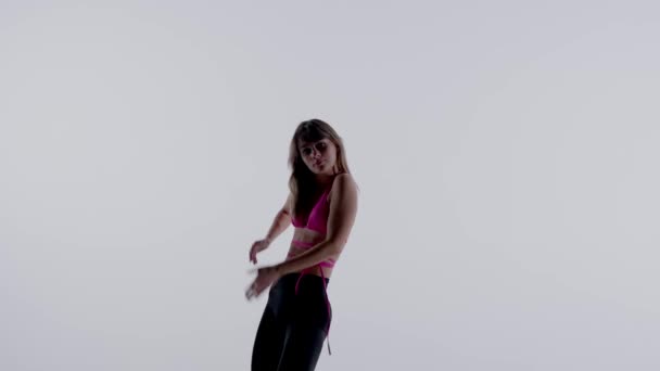 明るいピンクのブラジャー トップ レギンス ハイヒールを身に着けている若い女性は スタジオでエネルギッシュなヒールダンスを行い 孤立した白い背景を持っています ミディアムフル クリエイティブコンテンツ — ストック動画