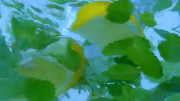 水漩涡创意广告的概念 近距离拍摄的水草涡旋 宏观工作室拍摄的壶与清澈的水拧涡旋 新鲜洋甘菊花 柠檬片和薄荷叶里面 — 图库视频影像