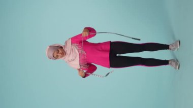 Tam ölçekli izole bir video, spor giyimli ve tesettürlü çekici bir genç kadın, Sheila. Boynuna mezura asıyor. Reklam yeri, promosyon, kilo verme.