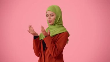Orta ölçekli izole bir video, tesettür ve duvak takan çekici bir genç kadını çekiyor. Dua etmek için ellerini havaya kaldırdı, gözlerini kapadı. İlanınız için yer, dini, kutsal.