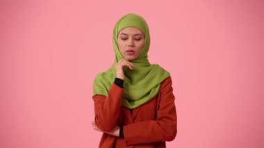 Orta ölçekli izole bir video, tesettür ve duvak takan çekici bir genç kadını çekiyor. O, bir plan düşünüyormuş gibi elini çenesine kaldırdı. Kültürel reklamın için yer.