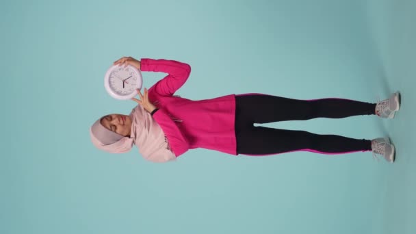 스포츠웨어와 히잡을 매력적인 여자를 사이즈 비디오 Sheila 그녀는 시계를 웃고있다 — 비디오